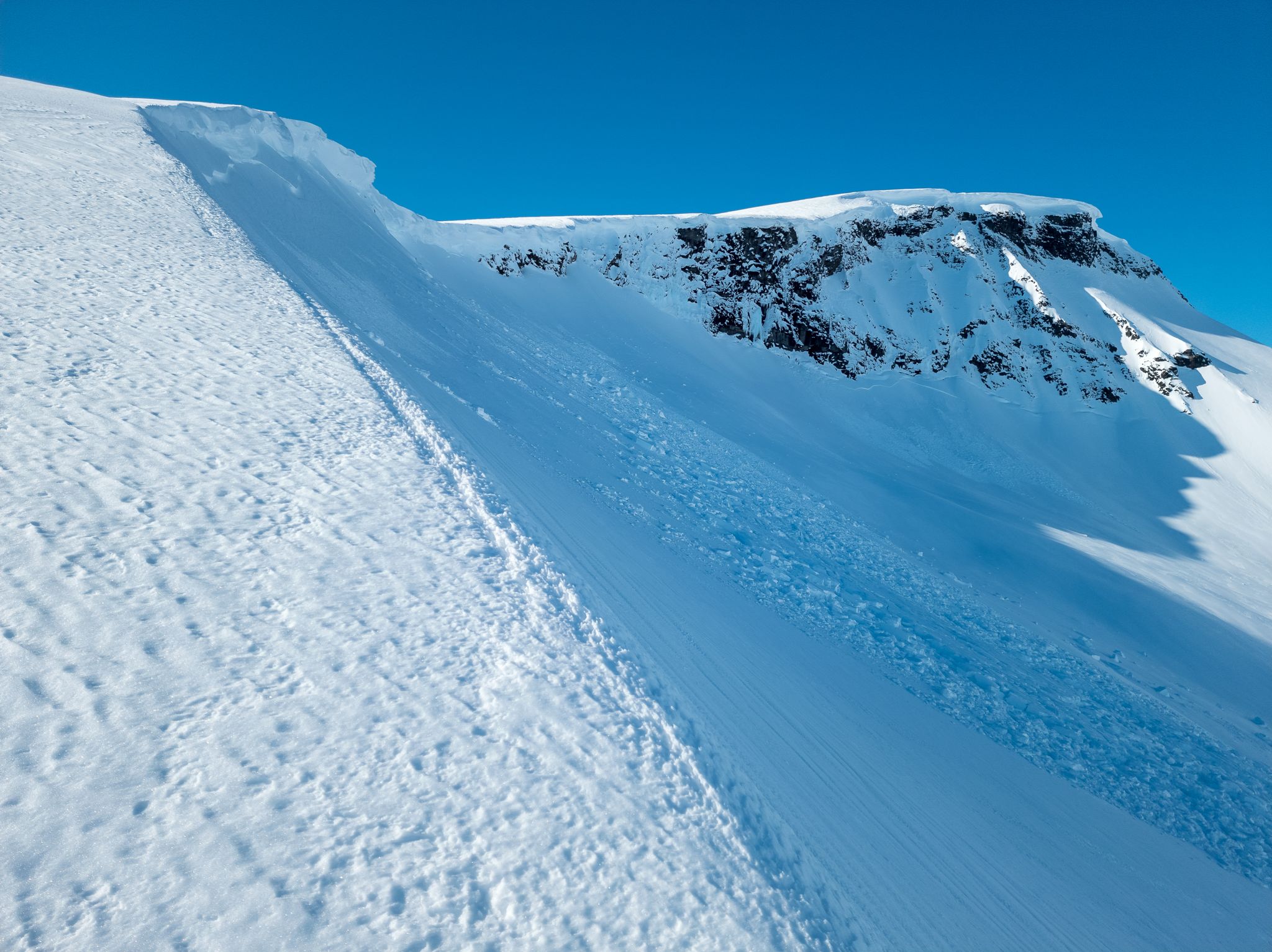 Stor snøskavl over en bratt fjellkant ved Auskjeret