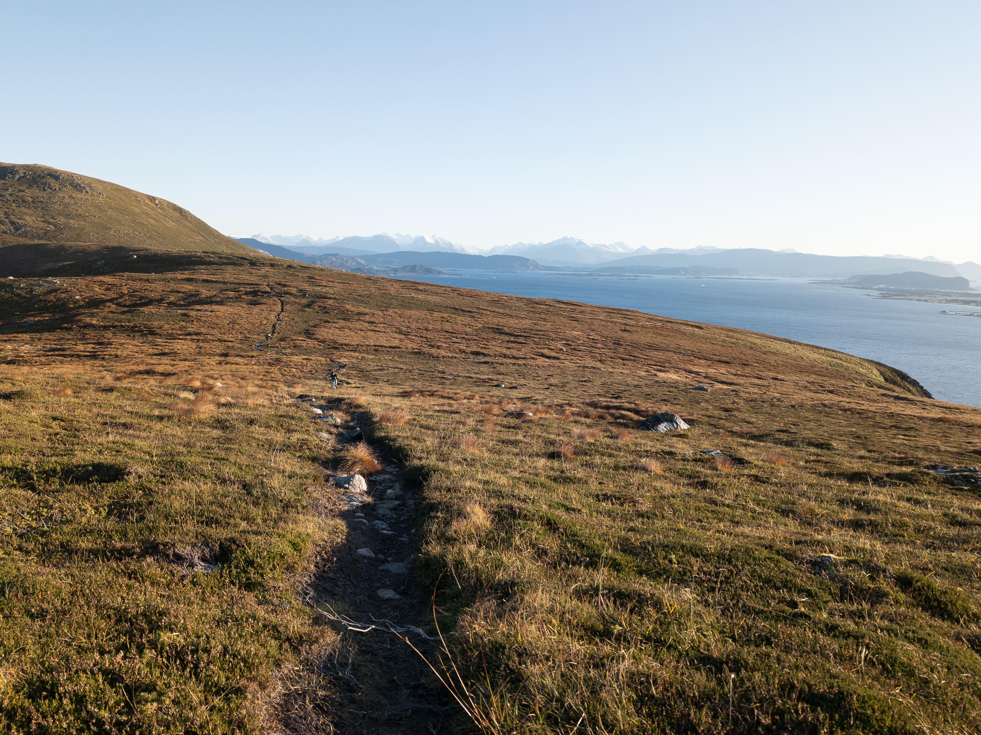Sti over den åpne fjellryggen på Lepsøya med en person, hav og fjell i bakgrunnen