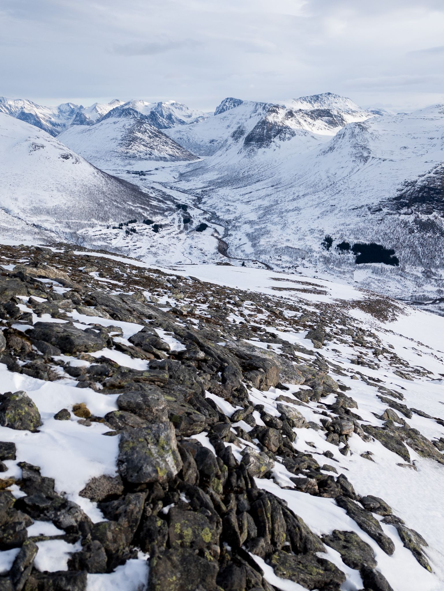 Utsikt ned en steinete og snødekt fjellside mot Stordalen