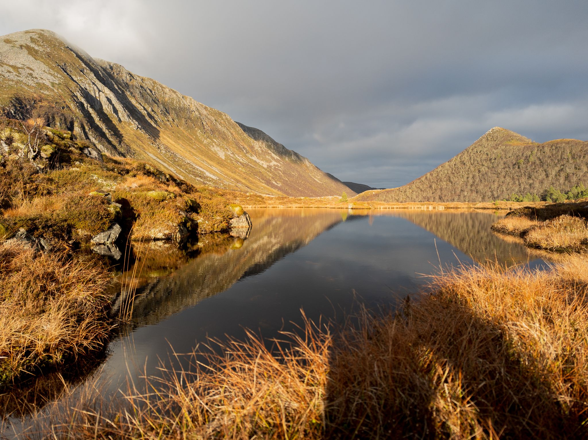 Stille fjellvann med Hildrehestens bratte rygg i lavt høstlys