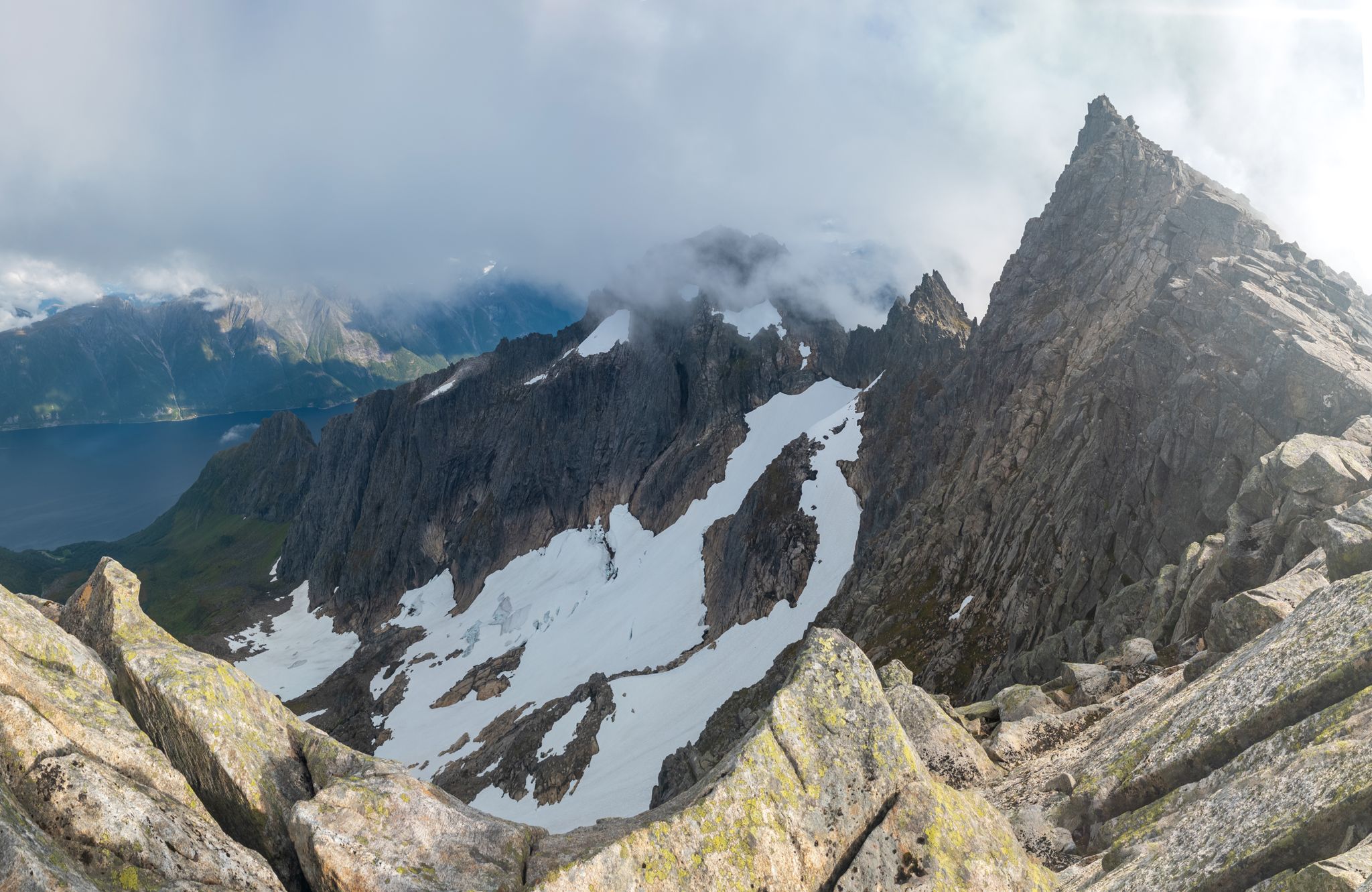 Taggete fjellrygg, bratte snøfelt og Hjørundfjorden sett fra Jønshornet