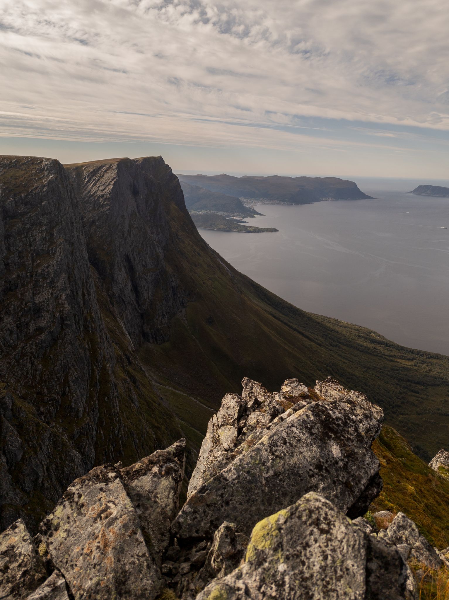 Bratt fjellkant ved Klovetinden med fjorden og kystlandskapet langt nedenfor
