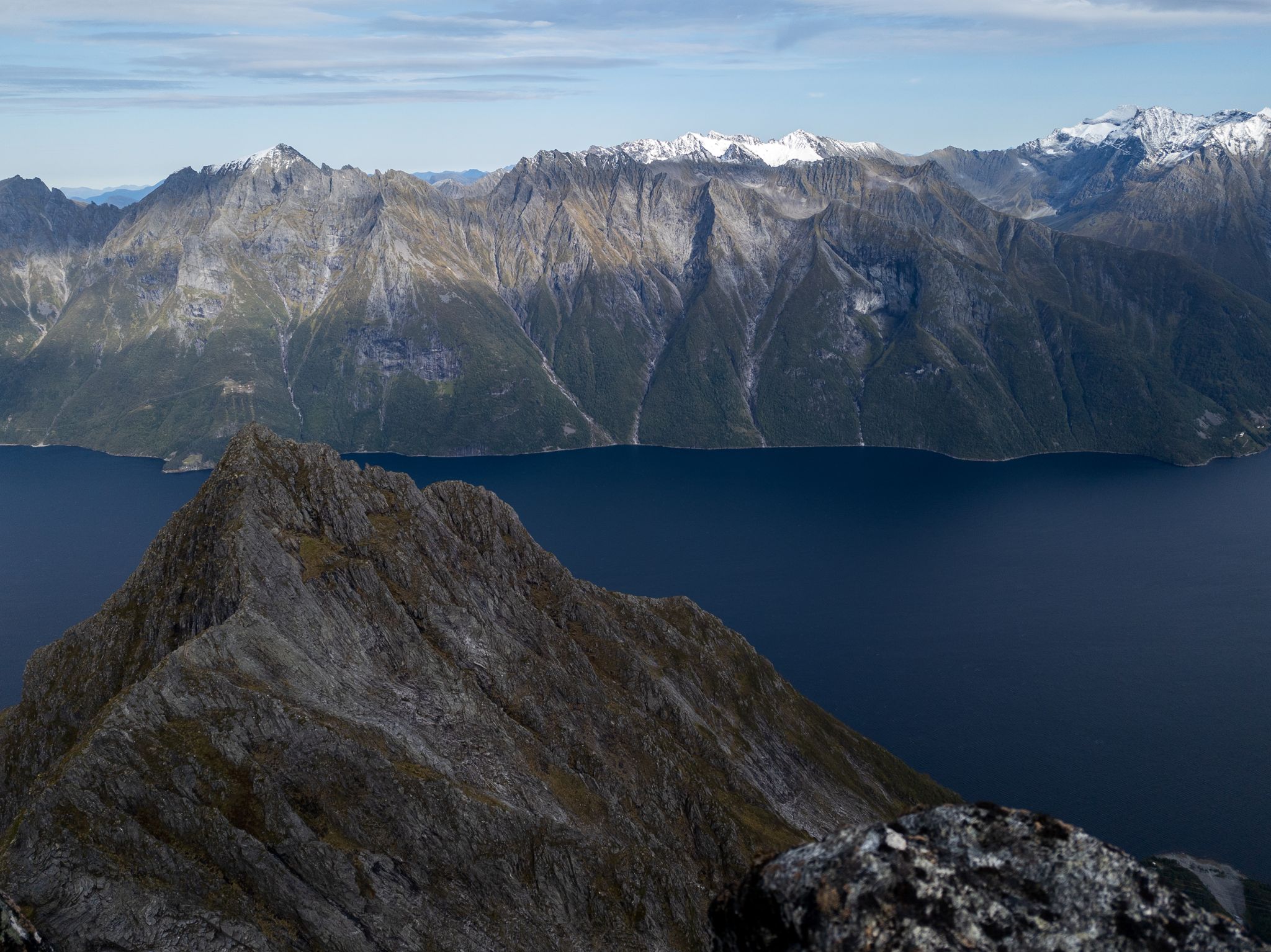 Smal steinrygg på Langenestinden med Hjørundfjorden og snødekte fjell i bakgrunnen