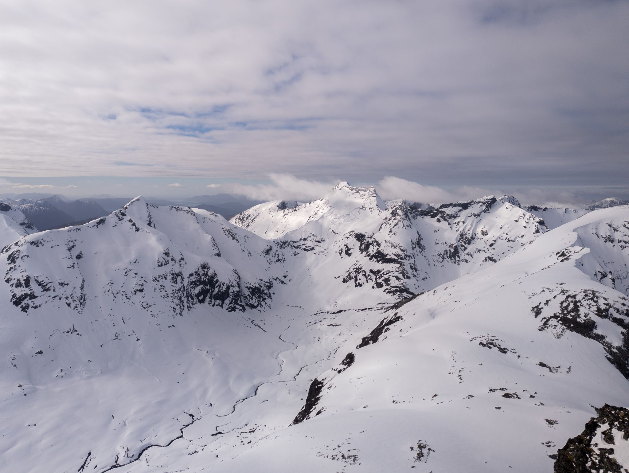 Panorama over snødekte fjell og daler fra toppområdet på Ørastolen