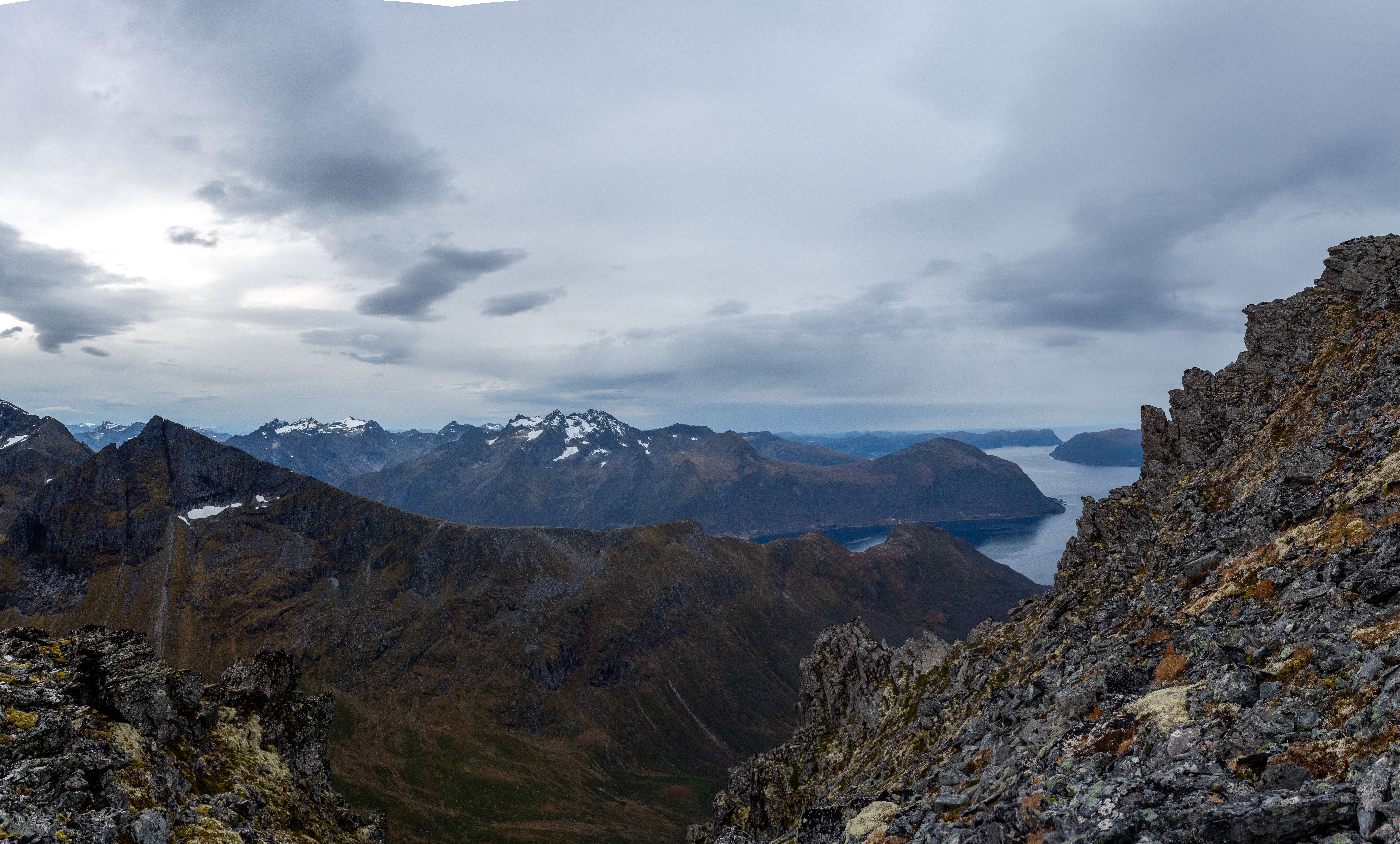 Steinete fjellterreng med fjord og tinder under et tungt skydekke sett fra Skopphornet