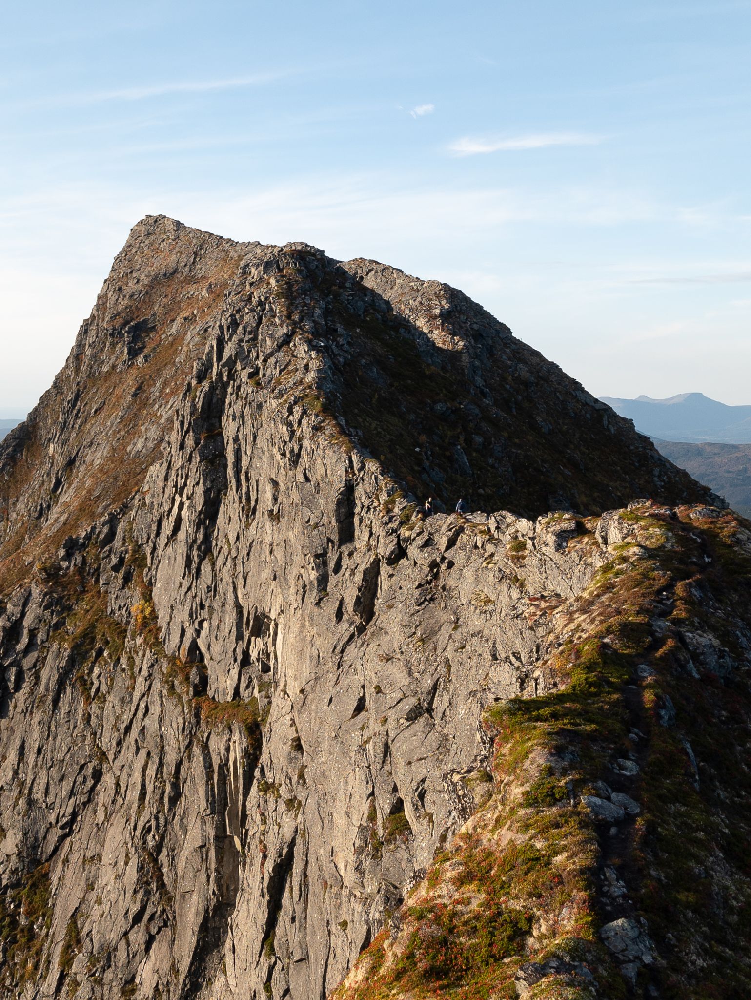 Turgåere på en smal fjellrygg med bratt bergvegg på venstre side